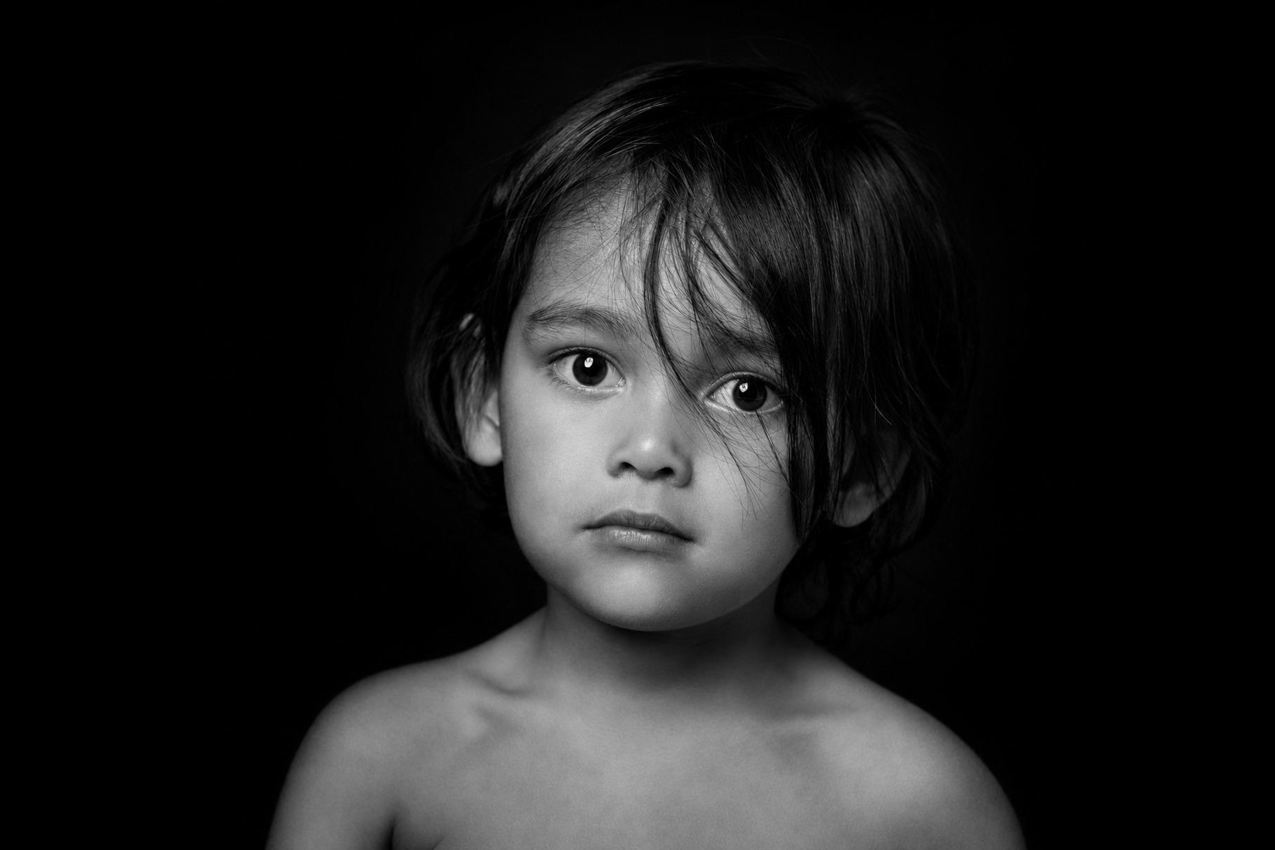 Zwart-witportret van een jongen voor een zwarte achtergrond, gefotografeerd in de studio in Zeist